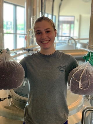 Food science major Samantha Martin holds up beer ingredients at Crooked Hammock Brewery.