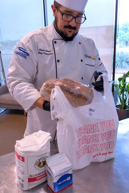Chef Ethan Starr bags some of the Culinary School of Fort Worth s freshly baked bread for a customer, along with a five pound sack of flour and a one pound bag of yeast.