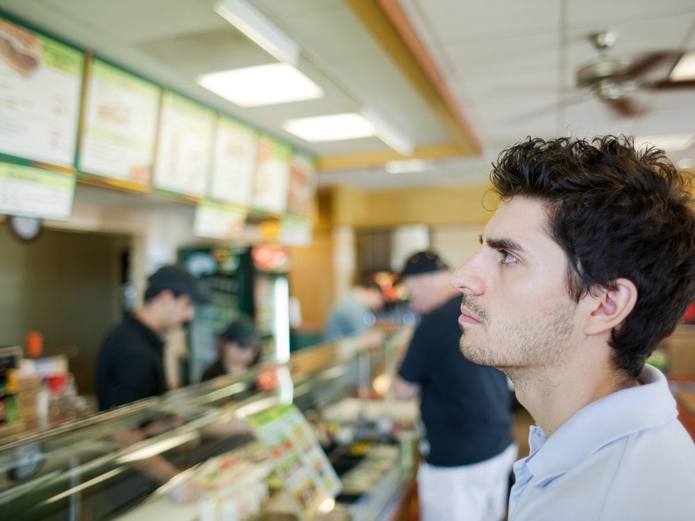 a man looks at an electronic restaurant menu behind a counter